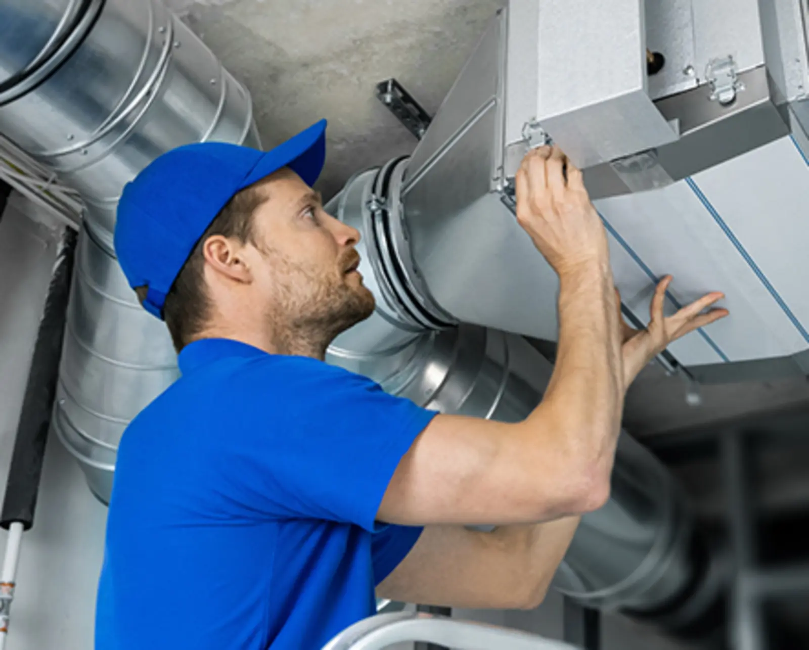 Techniker prüft Lüftungsanlage in einem Technikraum, Teil der technischen Gebäudeausrüstung
